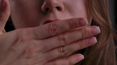 Elleriyle yanağına dudak parlatıcısı sürerken bir kadının yüzünün alt kısmının yakın çekimi..