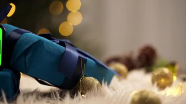 Yeşil ekranlı akıllı bir telefon düzgün paketlenmiş mavi hediye kutularının üzerinde oturur, şenlik temaları için mükemmel..