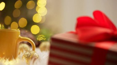 Yumuşak kürklü kurabiyeli sıcak sarı kupa, şenlikli süslemeler ve bokeh ışıklarıyla çevrili..