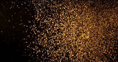 Küçük toz parçacıkları dumanlı havada rastgele uçar, nesneler için boş bir uzay şablonu. Altın tozunun birçok parçacığı ilgi odağı olan boş bir siyah zıt zemine düşer..