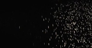 Küçük toz parçacıkları dumanlı havada rastgele uçar, nesneler için boş bir uzay şablonu. Pek çok parıldayan barut parçacıkları ışık ışınlarındaki zıt, boş bir zıt arkaplana düşer. Yavaş çekim.