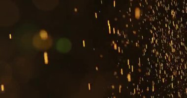 Küçük toz parçacıkları dumanlı havada rastgele uçar, nesneler için boş bir uzay şablonu. Altın tozunun birçok parçacığı ilgi odağı olan boş bir siyah zıt zemine düşer. Yavaş çekim.