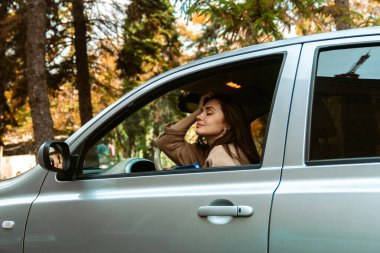 Genç bir kadın park halindeki bir arabada dinleniyor. Etrafı doğayla çevrili huzurlu bir anın tadını çıkarıyor..