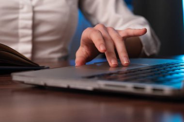 Bir dizüstü bilgisayarın klavyesine yazı yazan, bir iş yeri senaryosu tasvir eden yakın çekim elleri.