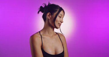 Genç bir Koreli model, pembe neon ışıklarla aydınlatılmış bir stüdyoda poz veriyor. Konsept güzellik, moda ve doğal kadınsı güzellik..