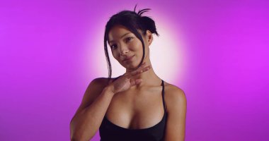 Genç bir Koreli model, pembe neon ışıklarla aydınlatılmış bir stüdyoda poz veriyor. Konsept güzellik, moda ve doğal kadınsı güzellik..