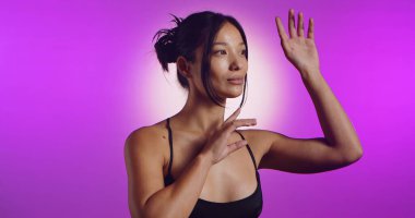 Genç bir Koreli model, pembe neon ışıklarla aydınlatılmış bir stüdyoda poz veriyor. Konsept güzellik, moda ve doğal kadınsı güzellik..