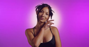 Genç bir Koreli model, pembe neon ışıklarla aydınlatılmış bir stüdyoda poz veriyor. Konsept güzellik, moda ve doğal kadınsı güzellik..