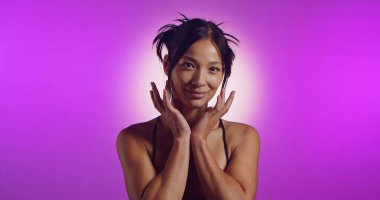 Genç bir Koreli model, pembe neon ışıklarla aydınlatılmış bir stüdyoda poz veriyor. Konsept güzellik, moda ve doğal kadınsı güzellik..