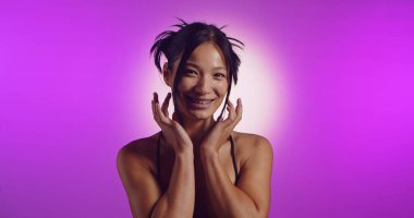 Genç bir Koreli model, pembe neon ışıklarla aydınlatılmış bir stüdyoda poz veriyor. Konsept güzellik, moda ve doğal kadınsı güzellik..