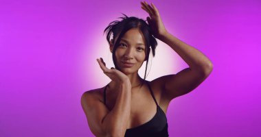 Genç bir Koreli model, pembe neon ışıklarla aydınlatılmış bir stüdyoda poz veriyor. Konsept güzellik, moda ve doğal kadınsı güzellik..