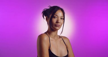 Genç bir Koreli model, pembe neon ışıklarla aydınlatılmış bir stüdyoda poz veriyor. Konsept güzellik, moda ve doğal kadınsı güzellik..