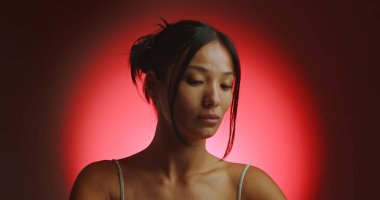 Spot ışığından kırmızı bir daire içinde genç bir Koreli modelin portresi. Konsept güzellik, moda ve doğal kadınsı güzellik..