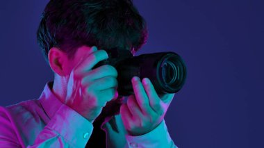 Profesyonel bir stüdyoda, yaratıcı neon ve pembe ışıklı bir stüdyoda fotoğraf çeken bir adamla sahne arkasında..