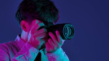 Profesyonel bir stüdyoda, yaratıcı neon ve pembe ışıklı bir stüdyoda fotoğraf çeken bir adamla sahne arkasında..