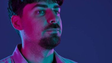 Profilde parlak pembe ve mor neon ışıklı bir adamın portresi koyu bir arka planda..