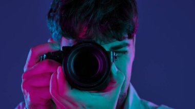 Profesyonel bir stüdyoda, yaratıcı neon ve pembe ışıklı bir stüdyoda fotoğraf çeken bir adamla sahne arkasında..