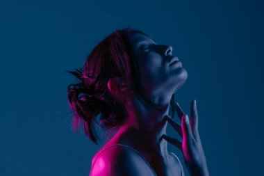 Genç bir Koreli model stüdyoda poz veriyor. Çarpıcı mavi ve pembe neon ışıklarla aydınlatılmış bir kadın. Renkli güzellik, moda ve doğal kadınsı güzellik..