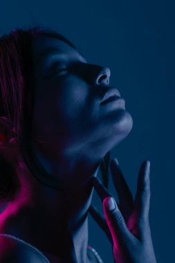 Genç bir Koreli model stüdyoda poz veriyor. Çarpıcı mavi ve pembe neon ışıklarla aydınlatılmış bir kadın. Renkli güzellik, moda ve doğal kadınsı güzellik..