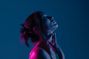 Genç bir Koreli model stüdyoda poz veriyor. Çarpıcı mavi ve pembe neon ışıklarla aydınlatılmış bir kadın. Renkli güzellik, moda ve doğal kadınsı güzellik..