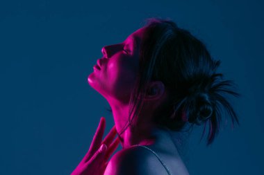 Genç bir Koreli model stüdyoda poz veriyor. Çarpıcı mavi ve pembe neon ışıklarla aydınlatılmış bir kadın. Renkli güzellik, moda ve doğal kadınsı güzellik..