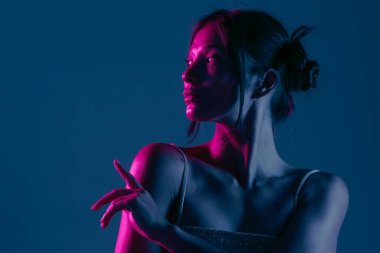 Genç bir Koreli model stüdyoda poz veriyor. Çarpıcı mavi ve pembe neon ışıklarla aydınlatılmış bir kadın. Renkli güzellik, moda ve doğal kadınsı güzellik..