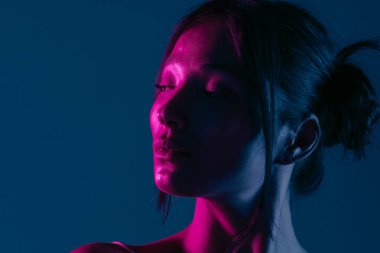 Genç bir Koreli model stüdyoda poz veriyor. Çarpıcı mavi ve pembe neon ışıklarla aydınlatılmış bir kadın. Renkli güzellik, moda ve doğal kadınsı güzellik..