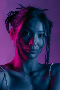 Genç bir Koreli model stüdyoda poz veriyor. Mor ve pembe neon ışıklarla aydınlatılmış bir kadın. Renkli güzellik, moda ve doğal kadınsı güzellik..