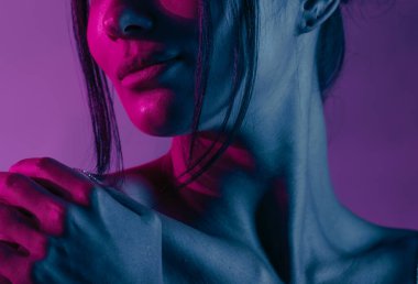 Genç bir Koreli model stüdyoda poz veriyor. Mor ve pembe neon ışıklarla aydınlatılmış bir kadın. Renkli güzellik, moda ve doğal kadınsı güzellik..