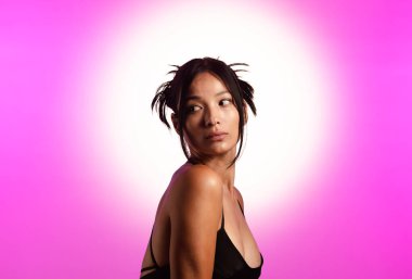 Genç bir Koreli model, pembe neon ışıklarla aydınlatılmış bir stüdyoda poz veriyor. Konsept güzellik, moda ve doğal kadınsı güzellik..