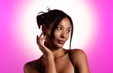 Genç bir Koreli model, pembe neon ışıklarla aydınlatılmış bir stüdyoda poz veriyor. Konsept güzellik, moda ve doğal kadınsı güzellik..