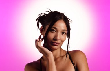 Genç bir Koreli model, pembe neon ışıklarla aydınlatılmış bir stüdyoda poz veriyor. Konsept güzellik, moda ve doğal kadınsı güzellik..
