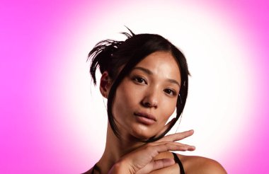 Genç bir Koreli model, pembe neon ışıklarla aydınlatılmış bir stüdyoda poz veriyor. Konsept güzellik, moda ve doğal kadınsı güzellik..