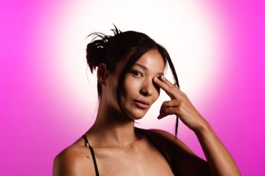Genç bir Koreli model, pembe neon ışıklarla aydınlatılmış bir stüdyoda poz veriyor. Konsept güzellik, moda ve doğal kadınsı güzellik..