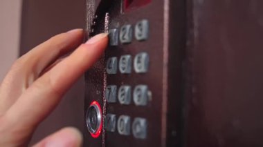 Bir elin açık hava güvenlik tuş takımına giriş kodunu girmesi, aydınlatma düğmesi, erişim kontrolü ve güvenlik teknolojisini temsil ediyor. Yavaş çekim.