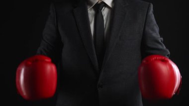 Takım elbiseli bir işadamı birbirine kırmızı boks eldivenleriyle vurur. Rekabet ve kararlılığı simgeler..