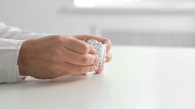 Beyaz kağıt çarşafı buruşturan ellerin kapatılması, bir çalışma istasyonundaki stres veya yaratıcılığı simgeliyor..