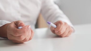 Beyaz bir iş gömleği giyen, beyaz bir masanın ya da eğitim kurumunun üzerindeki bir kalemin kapağını açıp kapatan bir kadının ellerini kapatın..