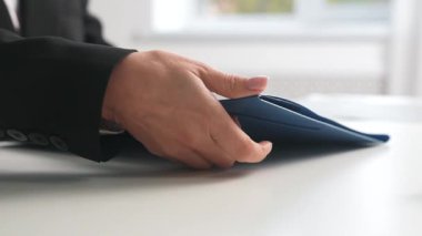 İçinde iş haritaları olan elastik bantlarla mavi bir klasörü kapatan bir kadın eli. Ofis belgeleri ve kırtasiye malzemeleri.