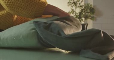 Sarı kazaklı bir kadının ellerinin cam bir masaya mavi kadife bir yastık koyduğu yakın plan bir odada rahat ve rahat bir his yaratır..