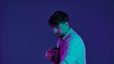 Profesyonel bir stüdyoda, yaratıcı neon ve pembe ışıklı bir stüdyoda fotoğraf çeken bir adamla sahne arkasında..