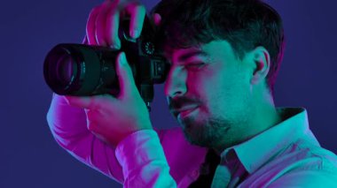 Profesyonel bir stüdyoda, yaratıcı neon ve pembe ışıklı bir stüdyoda fotoğraf çeken bir adamla sahne arkasında..