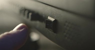 Elektronik ekipman, güç, teknoloji ve enerji kavramlarındaki siyah rockçı güç düğmesine yakın çekim. Bir insan eli düğmeyi açıp kapatır..