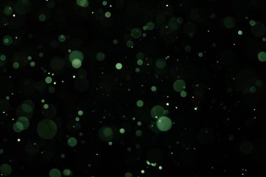 Karanlık bir arka planda yumuşak bulanık bokeh çemberleri rüya gibi ve soyut bir görsel etki yaratır. Siyah bir zemin üzerinde beyaz toz, toz veya kar parçacıkları izole. Üst üste efektli arkaplan.