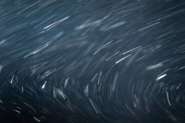 Toz parçacıkları ya da beyaz kar havada rastgele dağılır ve spot ışıkları altında siyah bir zeminde parlar. Üst üste efektli arkaplan.