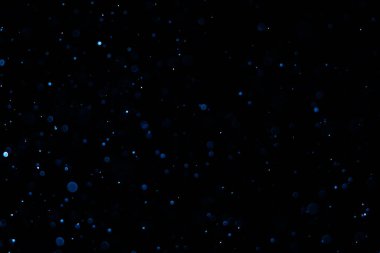 Siyah bir arka plan üzerinde Bir ışık ışını içinde yüzen toz yükselen küçük parçalar. Uzayda hızla hareket eden rüzgar tarafından uçurulmuş gibi rastgele dönüyor. Her biri bağımsız ve dinamik uçan.