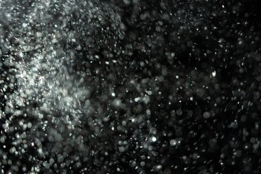 Küçük toz parçacıkları dumanlı havada rastgele uçuyor, reklam nesneleri için boş bir şablon. Beyaz toz parçacıkları loş ışıkta boş siyah zıt bir zıt arkaplan karşısında.