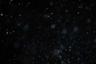 Siyah bir arka plan üzerinde Bir ışık ışını içinde yüzen toz yükselen küçük parçalar. Uzayda hızla hareket eden rüzgar tarafından uçurulmuş gibi rastgele dönüyor. Her biri bağımsız ve dinamik uçan.