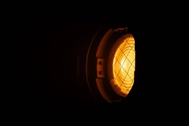 Karanlık bir odayı aydınlatan güçlü bir turuncu spot ışığını kapat ve dramatik bir ışık efekti yarat. Sahne arkasında ışıklandırma ekipmanları.