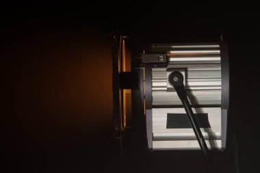 Stüdyo aydınlatma ekipmanları karanlıkta parlak turuncu bir ışık yayar ve profesyonel spot ışıklarının tasarımını ön plana çıkarır. Sahne arkasında ışıklandırma ekipmanları.